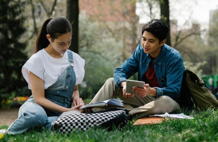 Two friends studying together in a park