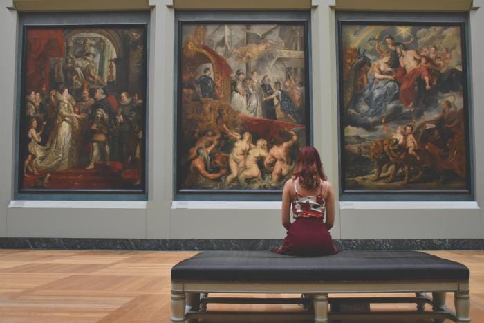 A woman sat looking at art in an art gallery